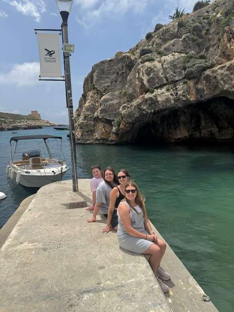 4 students sitting by a boat in Malta